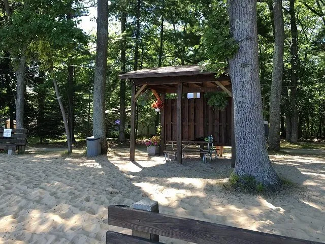 Wooden beach shelter on the sand among pine trees at Bass Lake