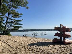 Kayak rack on the sandy Bass Lake beach with the swim dock in the distance