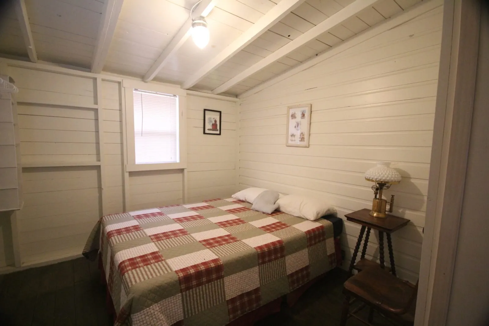 Bedroom in Dorothy Cottage with a plaid quilt and bedside lamp