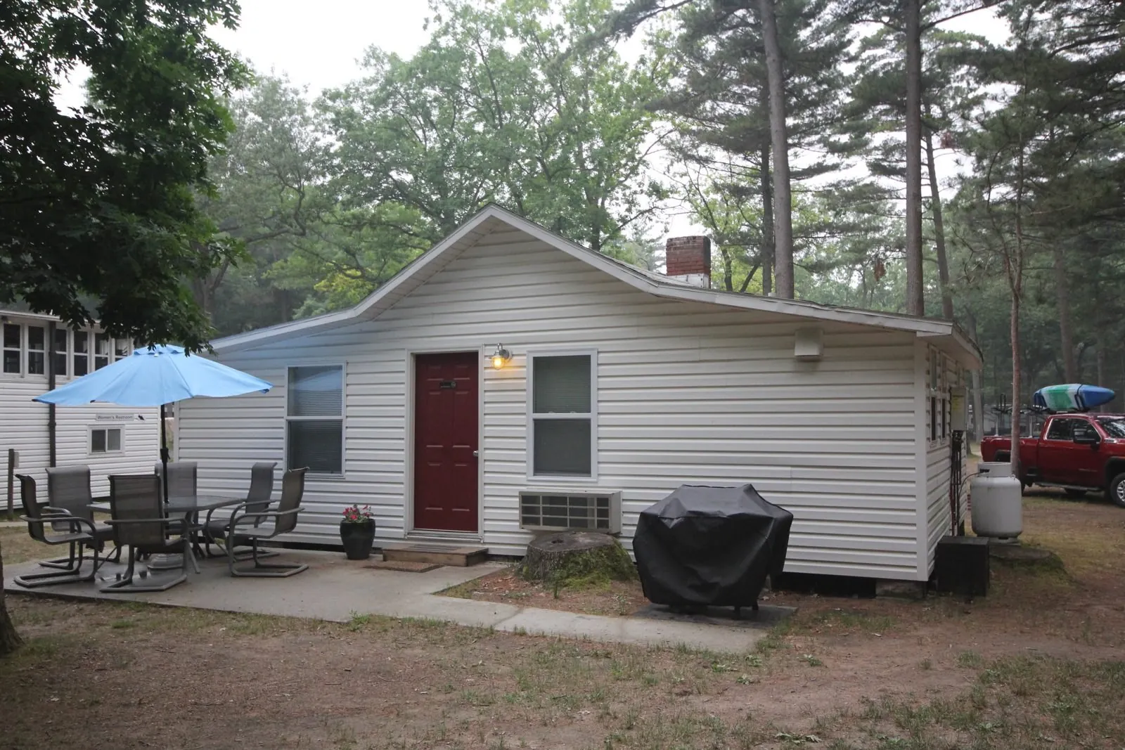Dorothy Cottage, a white cottage with a red door, patio seating and umbrella