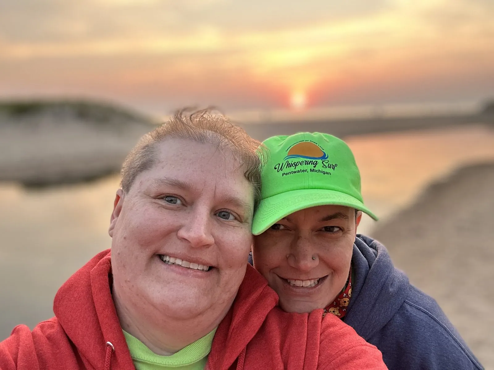 Drea and Amanda, the office and grounds work campers, smiling at sunset on the beach