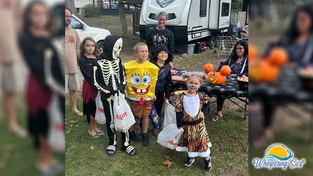 Kids in costumes trick-or-treating between decorated campsites