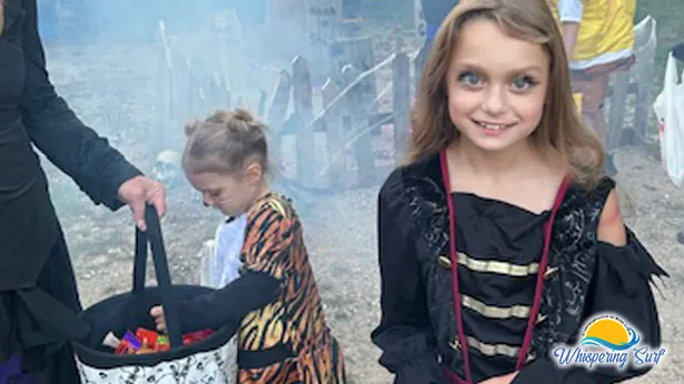 Young trick-or-treaters in costume collecting candy at a campsite