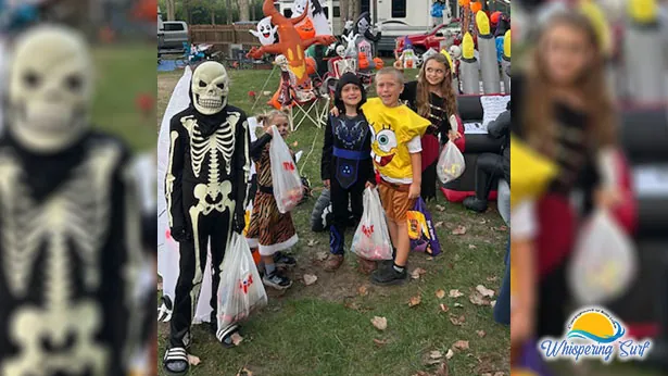 Costumed kids beside a campsite decorated with skeletons and pumpkins