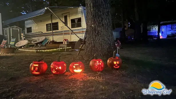 Row of glowing jack-o'-lanterns at a campsite after dark