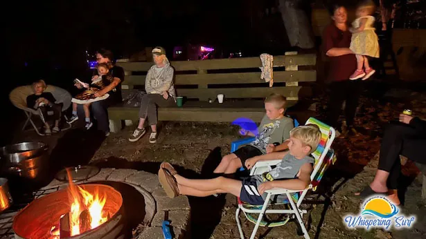 Campers roasting s'mores around the community fire ring at night