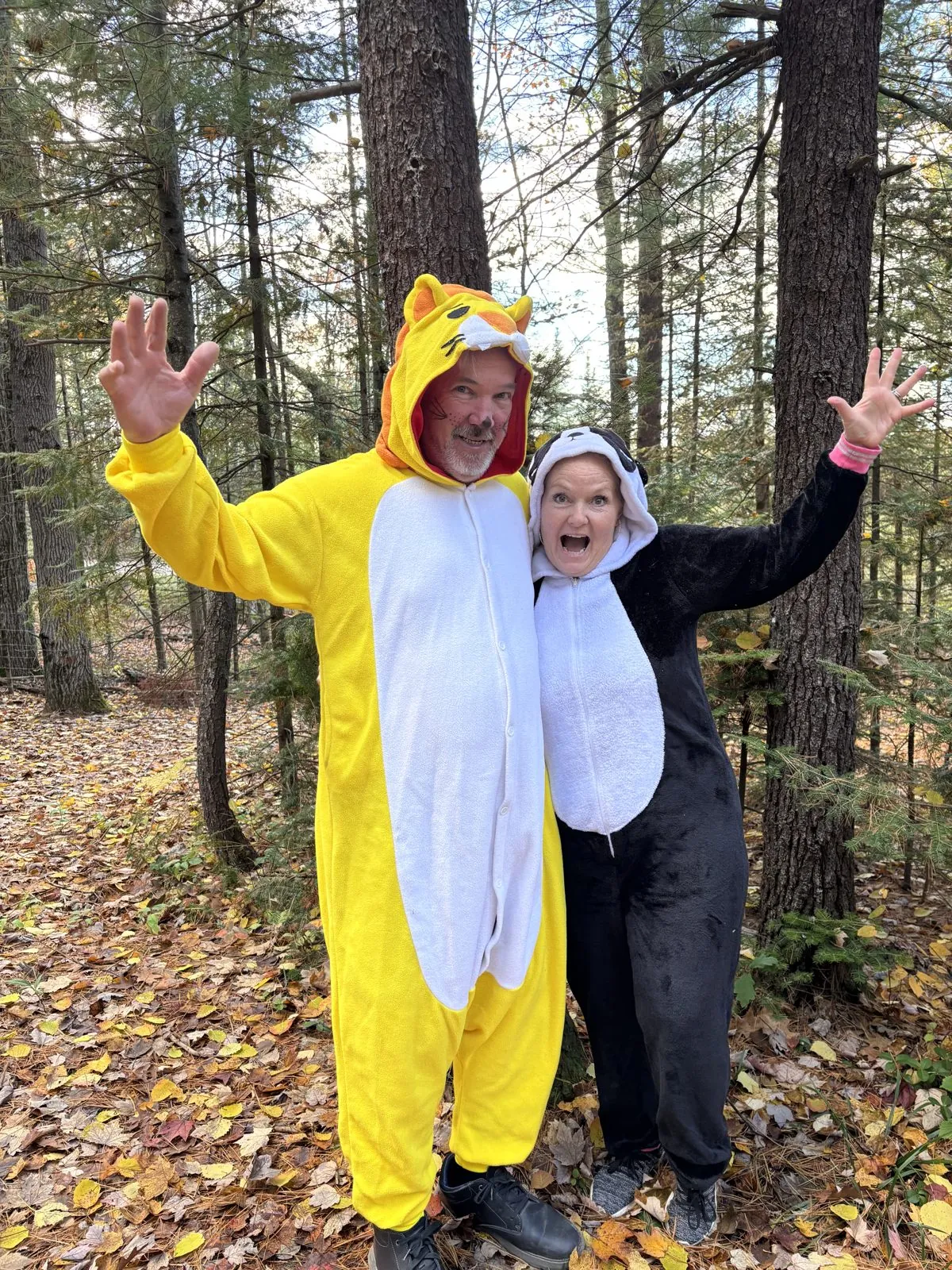 Ken and Jeannie in animal onesies waving among the pines